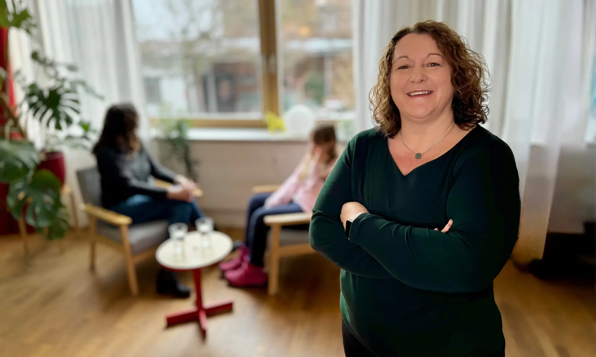 Systemische Beratung in Freising mit Jutta Hesse im Vordergrund und Familie im Gespräch im Hintergrund